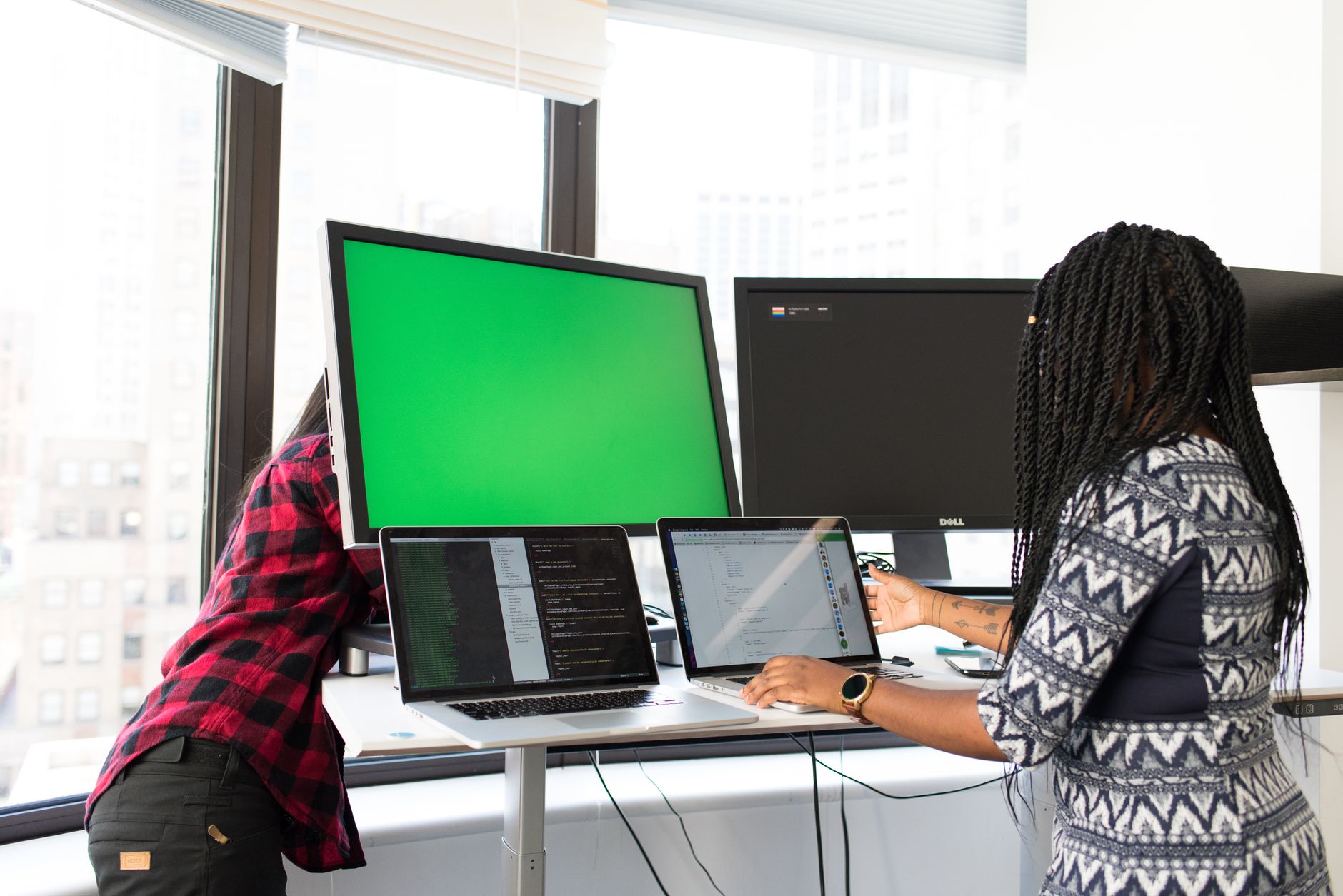 Two team members monitoring dashboards on laptops and screens